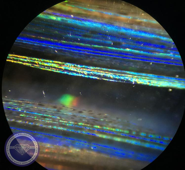 Fine platelets oriented in planes along the length of crystal,these planes are stringers of magnetite displayed bright iridescence colors and angular features in a Natural Cats Eye Scapolite, viewed with oblique fiber-optic illumination. - Photo by: Naveed Zafar G.G., AJP (GIA).